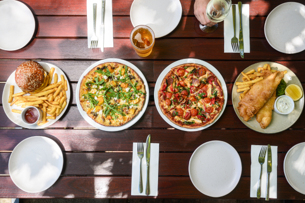 Dining table with four plates of food from various pizza restaurants in Perth