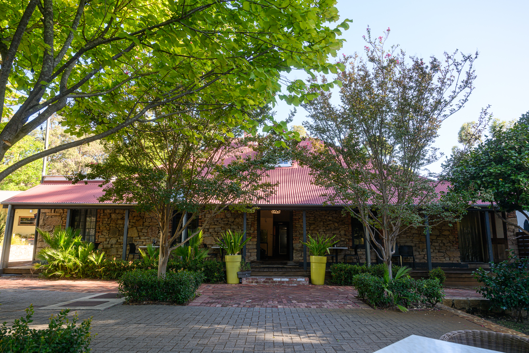 hotel entrance with a cozy courtyard at the Mahogany Creek Inn, showcasing a rustic wooden door and lush greenery.